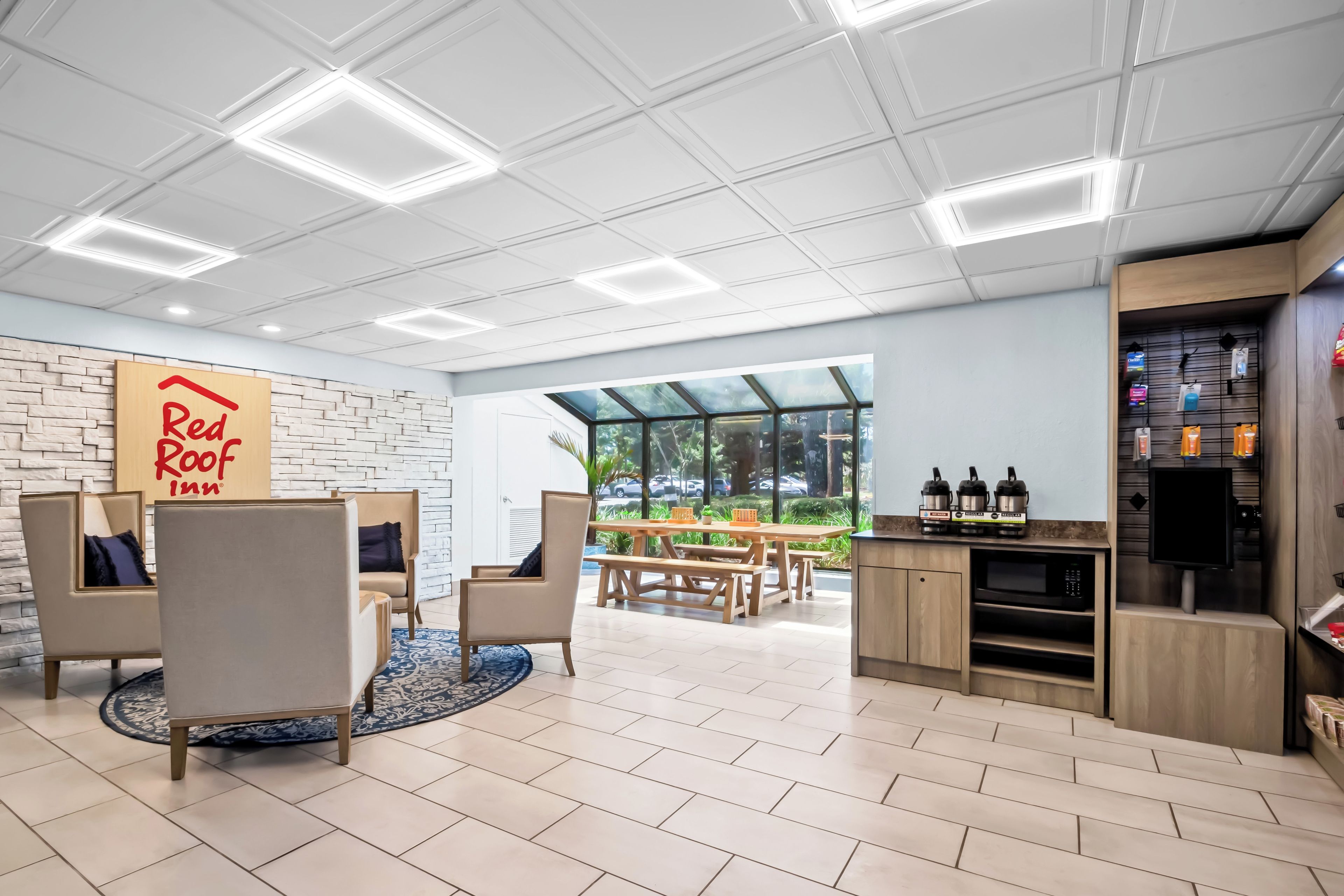 A modern interior with a Red Roof Inn sign, a dining area with a view, and a kitchenette with appliances.