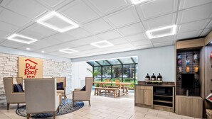 A modern interior with a Red Roof Inn sign, a dining area with a view, and a kitchenette with appliances. - Red Roof Inn Myrtle Beach Hotel - Market Common (Myrtle Beach)