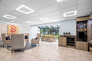 Un intérieur moderne, avec une enseigne Red Roof Inn, un espace repas offrant une vue agréable et une kitchenette équipée d’appareils électroménagers.