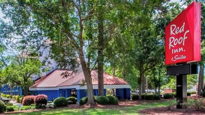 A Red Roof Inn & Suites with a red roof, surrounded by lush greenery and a well-maintained lawn. - Red Roof Inn Myrtle Beach Hotel - Market Common (Myrtle Beach)