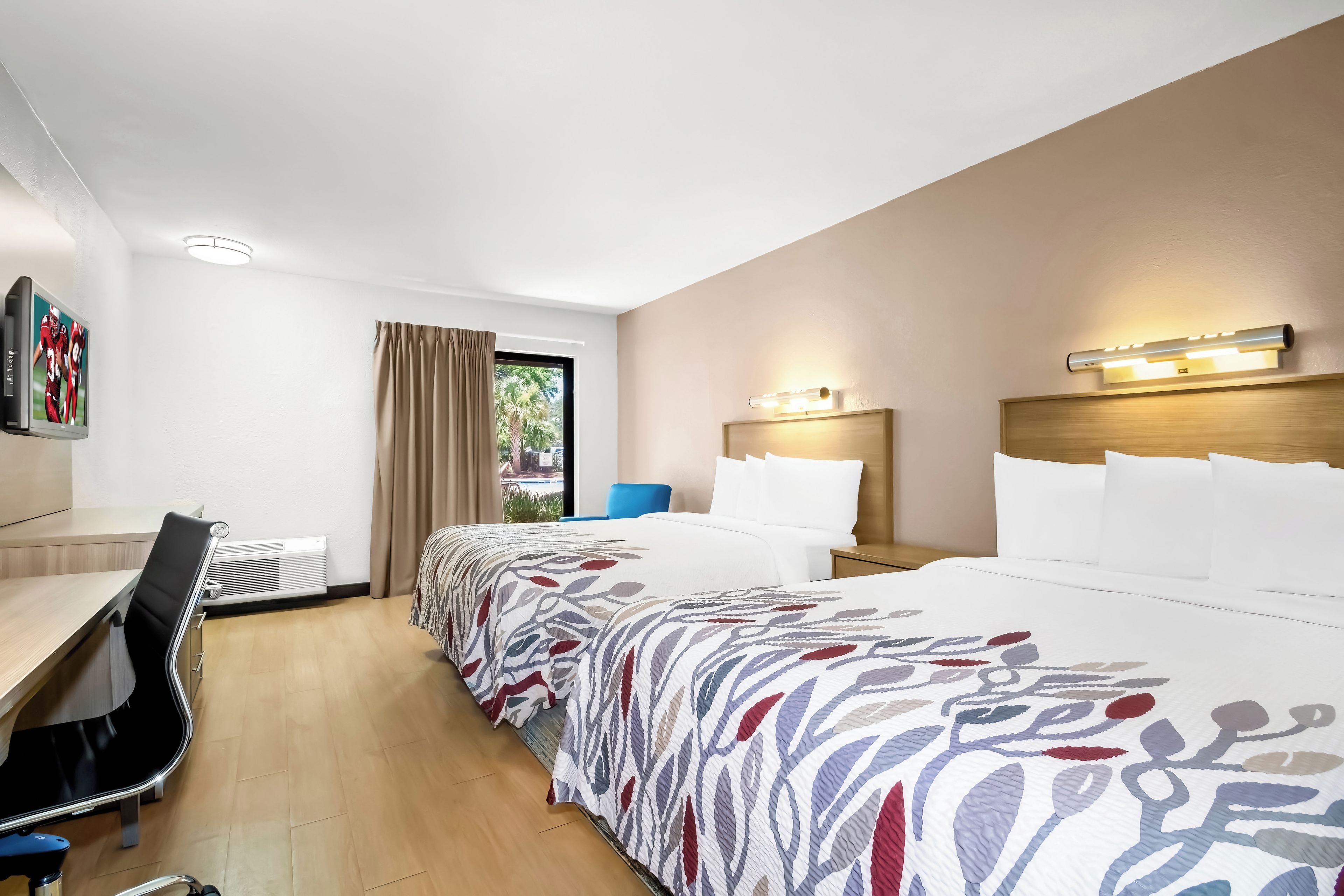 A hotel room with a bed, bedside tables, a desk, a chair, and a window with curtains.