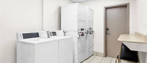 A laundry room with a washing machine, dryers, and a small table with chairs.