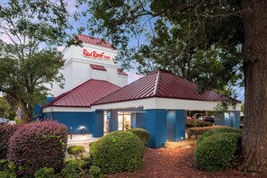 A Red Roof Inn with a red roof and white walls, surrounded by trees and shrubs. - Red Roof Inn Myrtle Beach Hotel - Market Common (Myrtle Beach)
