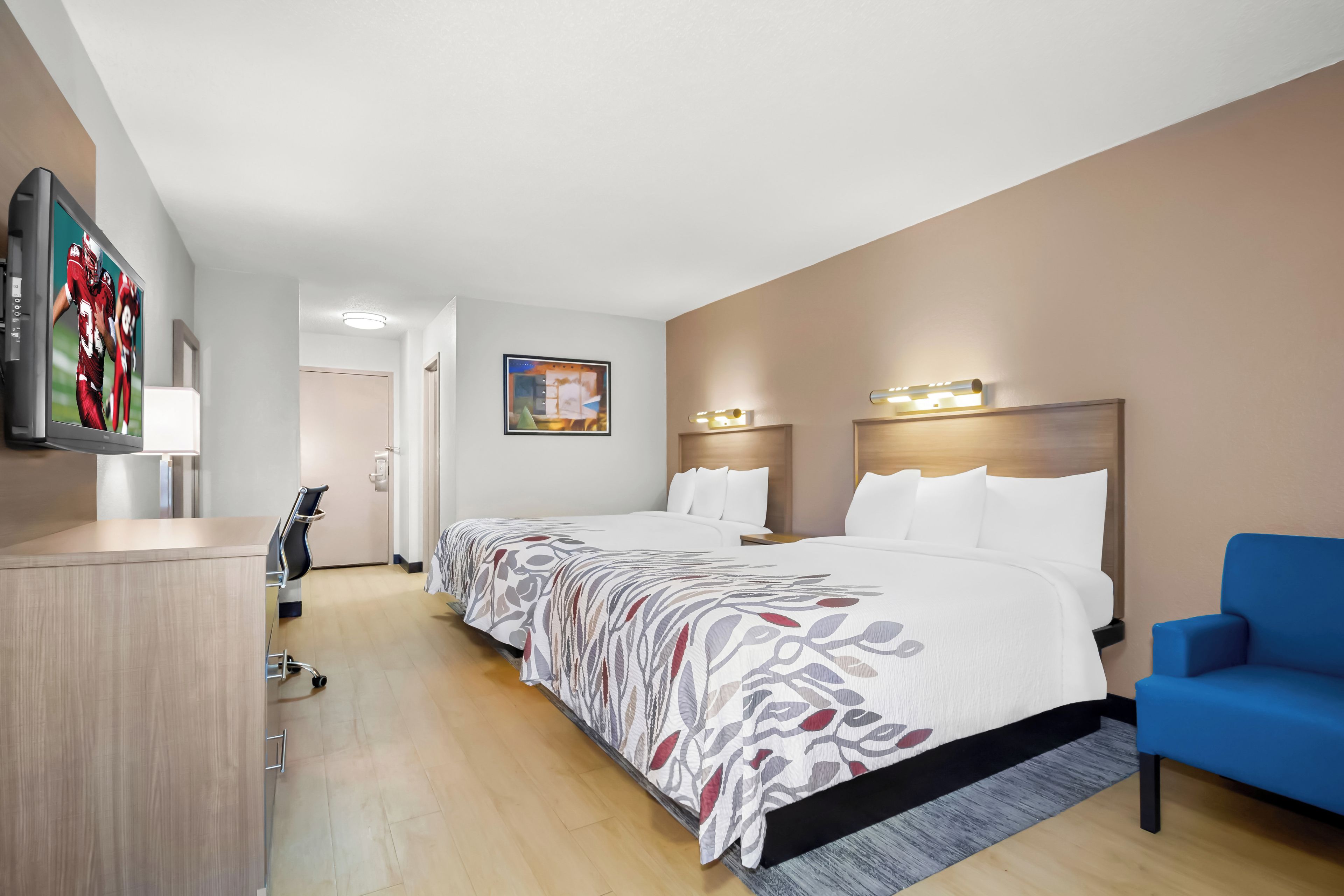 Una habitación de hotel con una cama grande, un escritorio, una silla y un televisor.