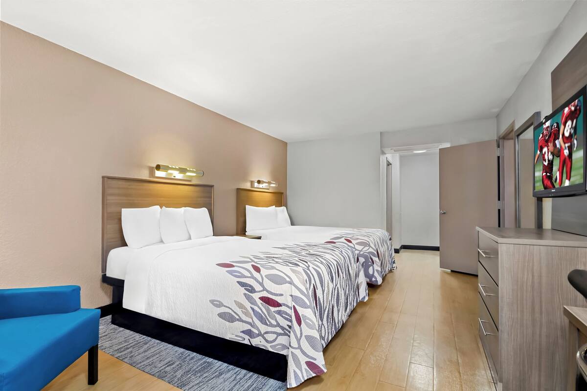 Una habitación de hotel con una cama grande, un escritorio, una silla y un televisor.