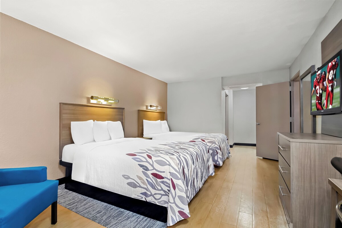 A hotel room with a bed, a desk, a chair, and a television.