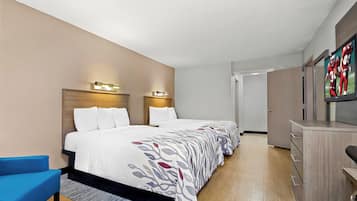 A hotel room with a bed, a desk, a chair, and a television.