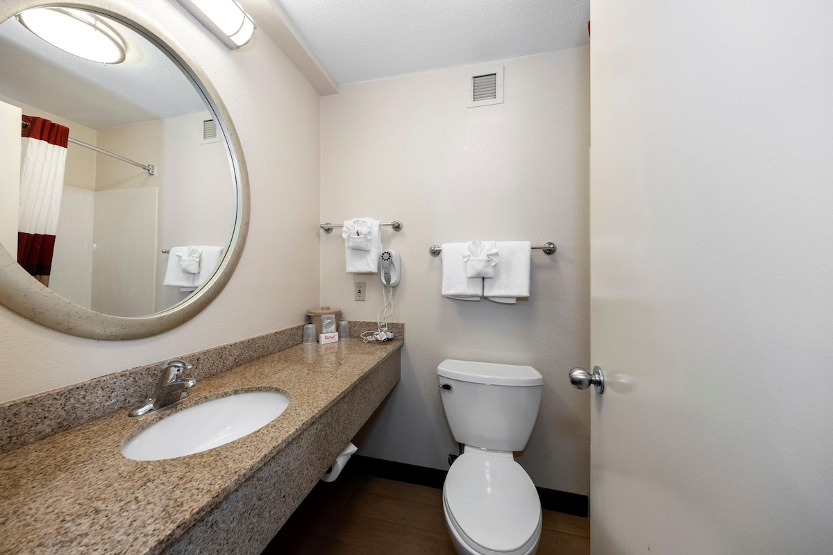 A bathroom with a granite countertop sink, a white toilet, and a mirror.