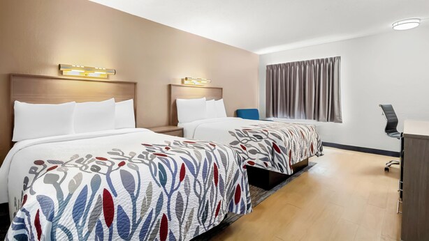 A hotel room with two beds, a desk, and a window with curtains. - Red Roof Inn Myrtle Beach Hotel - Market Common (Myrtle Beach)