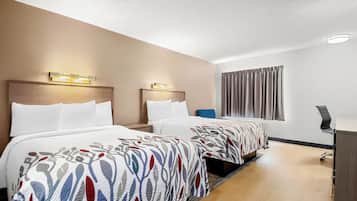 A hotel room with two beds, a desk, and a window with curtains.