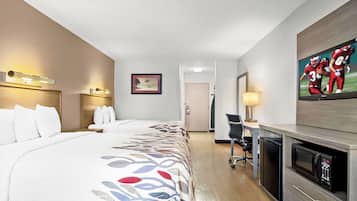 A hotel room with a bed, a desk, a television, and a door.