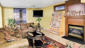Una sala de estar con chimenea, televisor y una estantería llena de revistas.