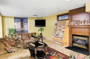 A living room with a fireplace, a television, and a wall of magazines.