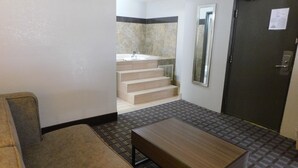 Habitación de hotel con sofá, una mesa de madera, un espejo y una puerta.