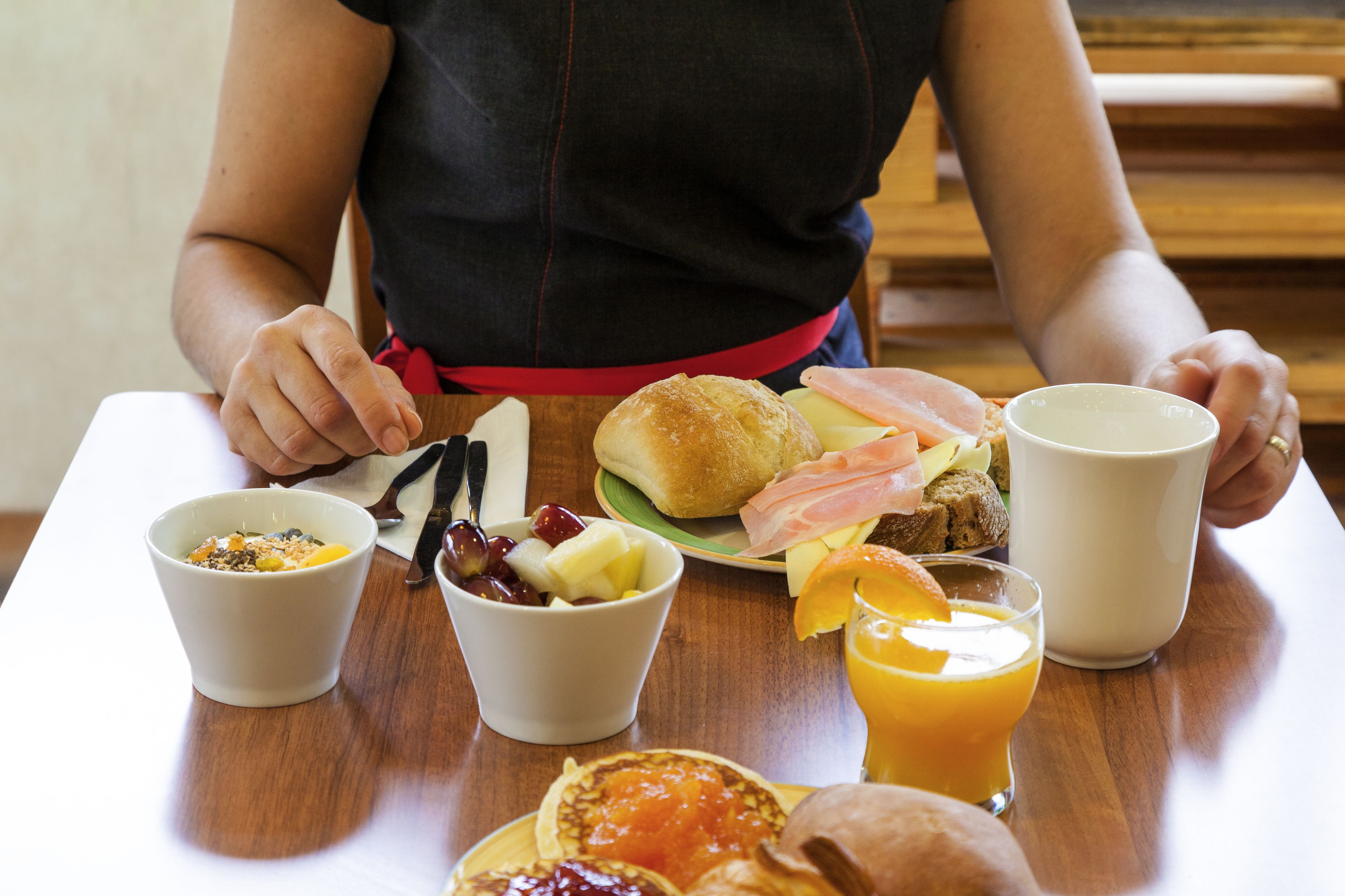 A breakfast table with a variety of food items including a bowl of cereal, a plate with eggs, toast, and a glass of orange juice.