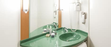 A bathroom with a green sink, a mirror, a white towel, and a phone.