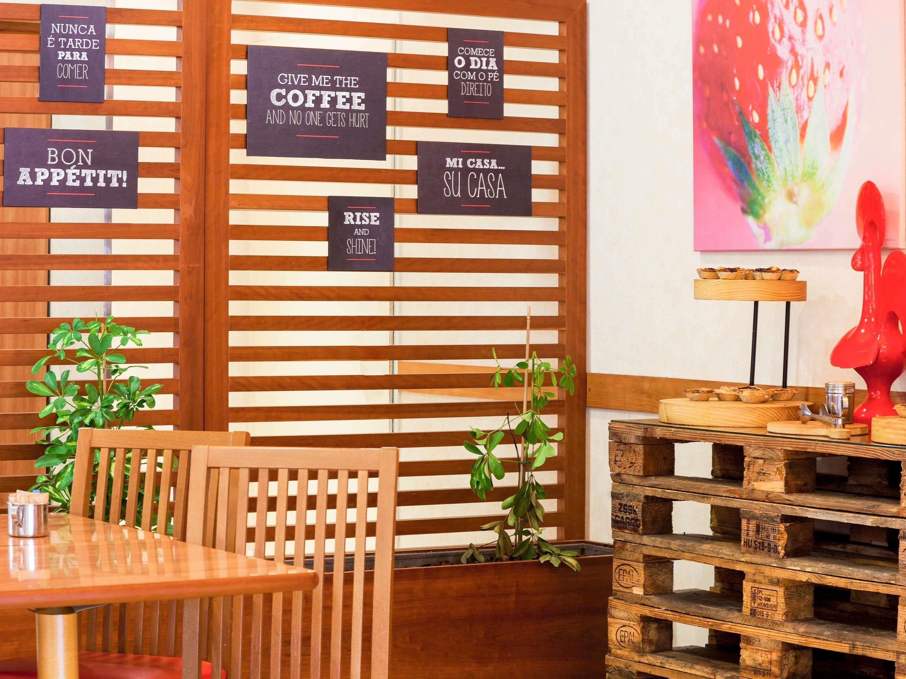 A cozy café interior with wooden slats, a wooden table, chairs, and a red sculpture.