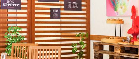 A cozy café interior with wooden slats, a wooden table, chairs, and a red sculpture.
