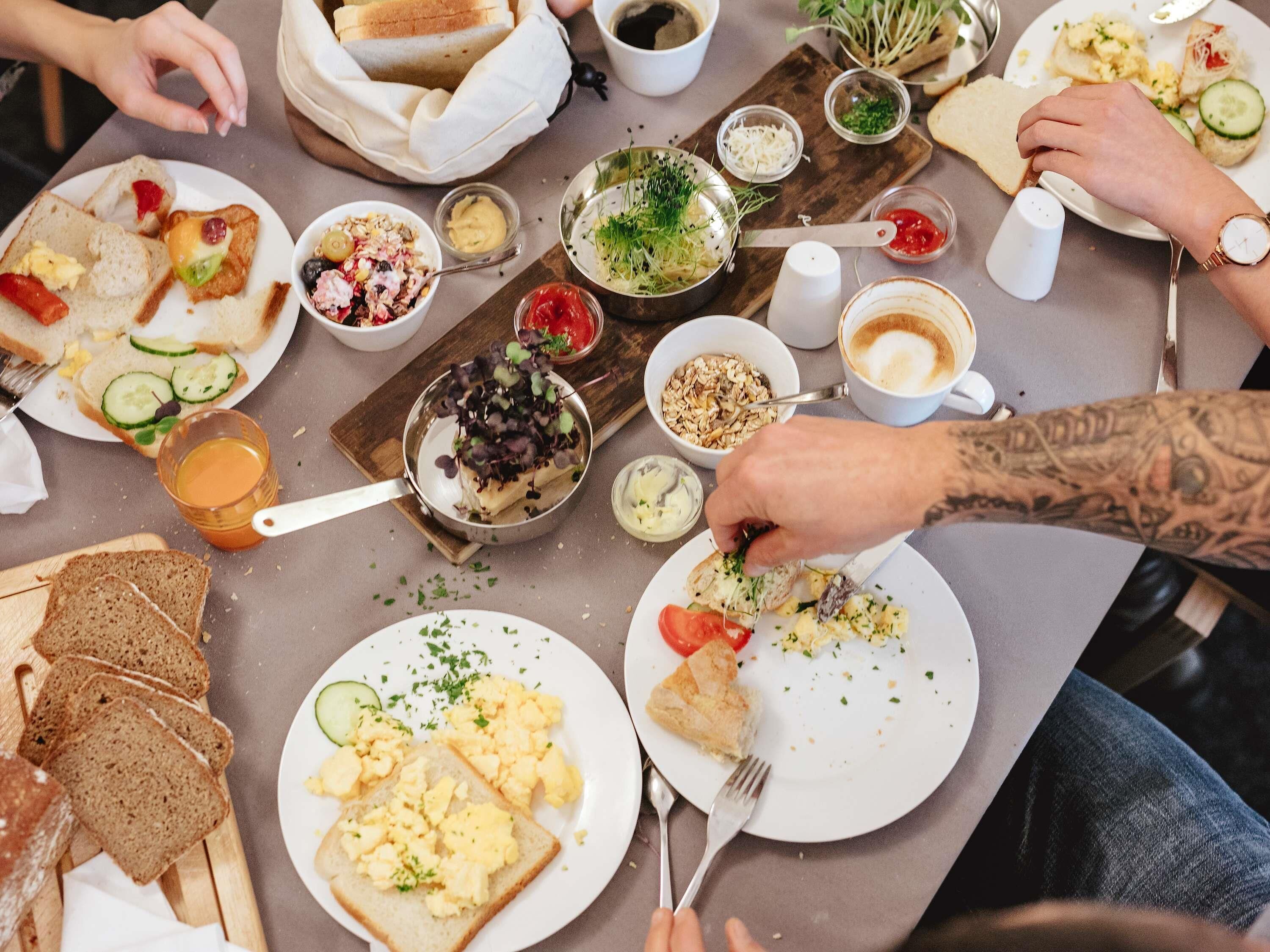 A dining table with various breakfast items including toast, scrambled eggs, and fresh vegetables.