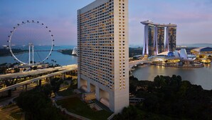 A high-rise hotel with a modern design, located near a waterfront with a Ferris wheel and a distinctive bridge. - The Ritz-Carlton, Millenia Singapore (Singapore)