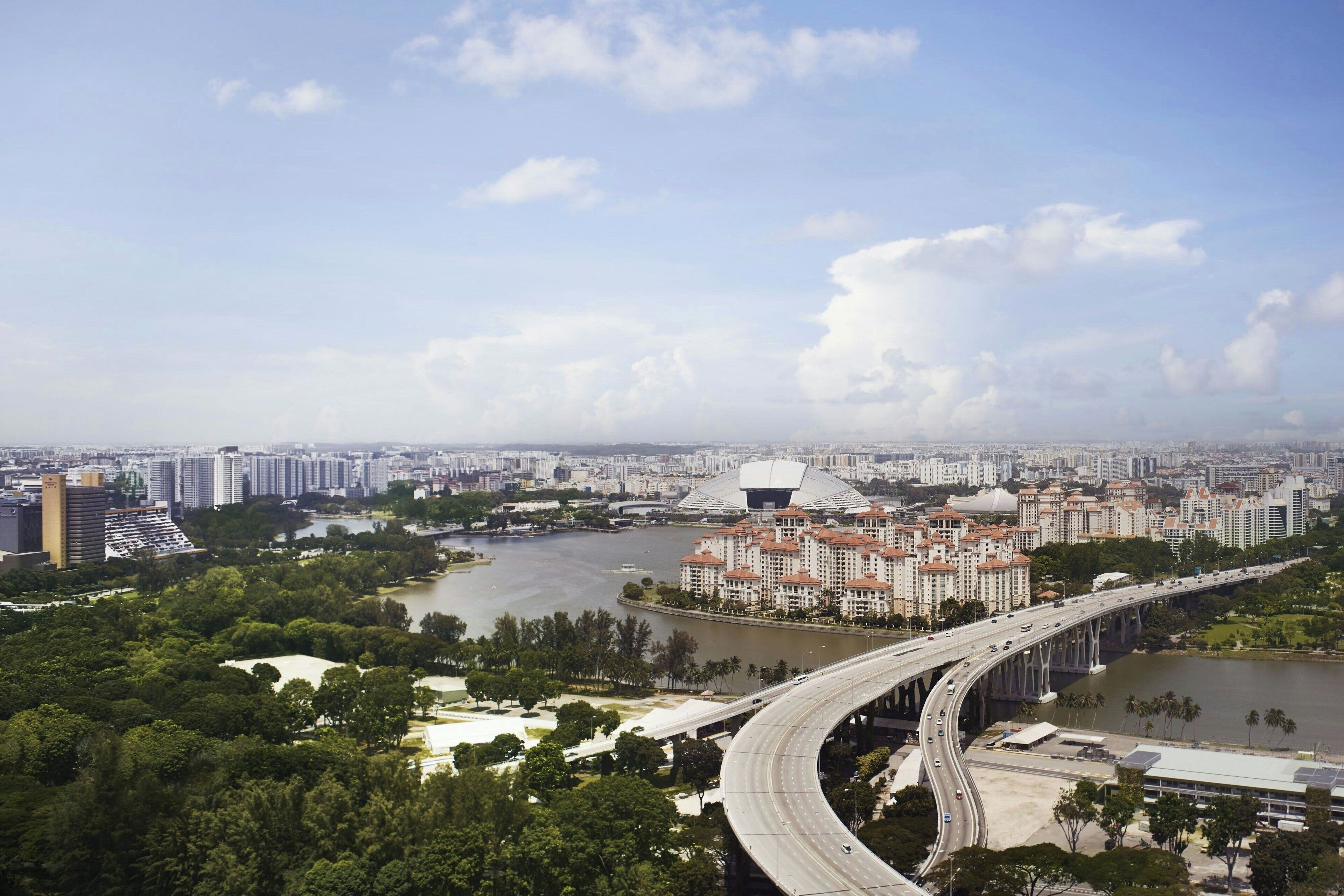 A cityscape with a river, a bridge, and a large stadium.
