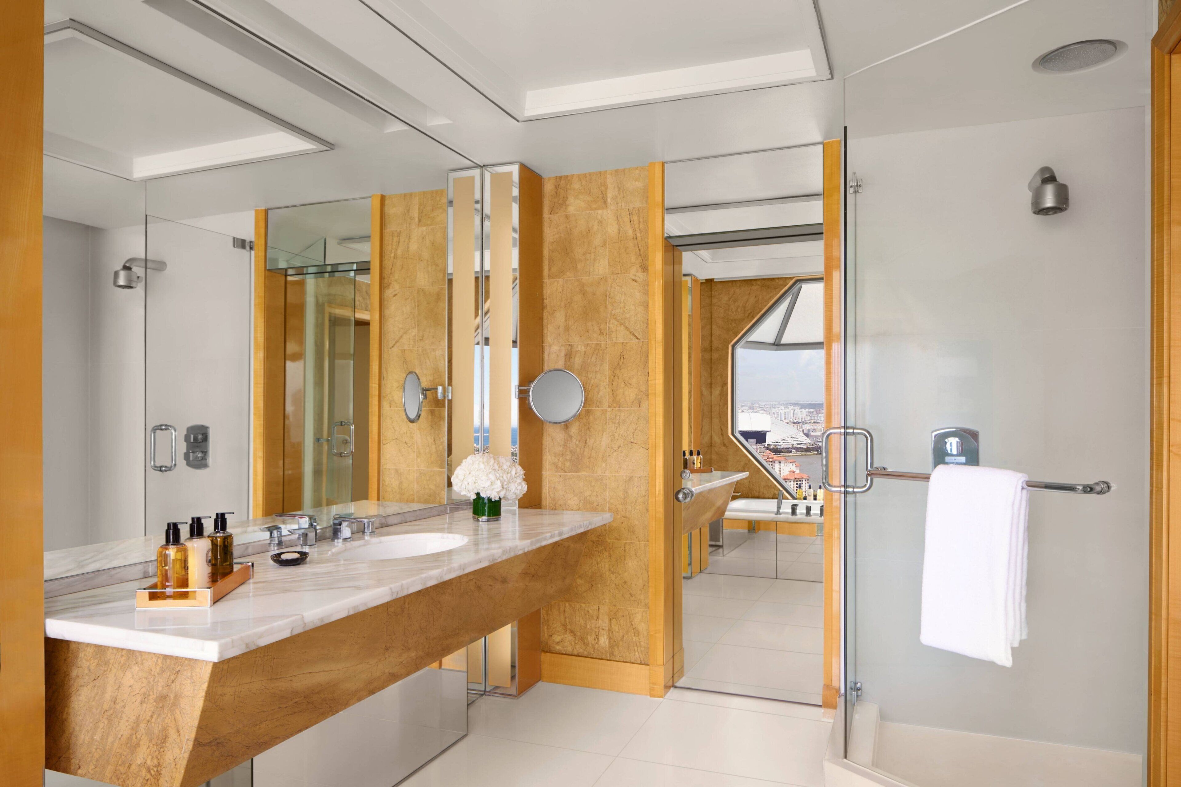Un baño moderno con un espejo grande, ducha y tocador con encimera de mármol.
