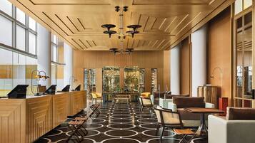 En moderne hotellobby med en træreception, siddeområde og et mønstret gulv.