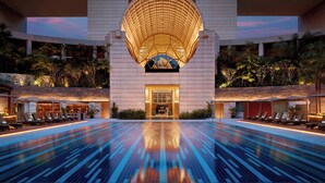 A modern hotel with a large pool, a distinctive circular skylight, and a well-lit entrance. - The Ritz-Carlton, Millenia Singapore (Singapore)