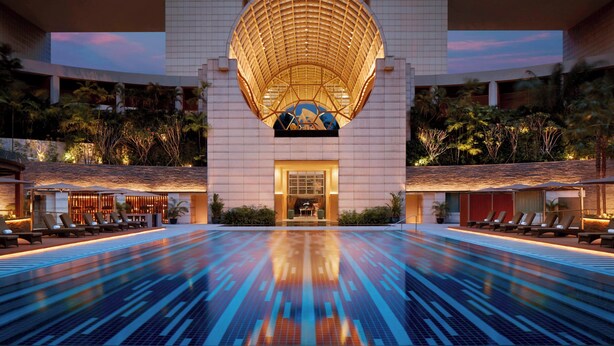 A modern hotel with a large pool, a distinctive circular skylight, and a well-lit entrance. - The Ritz-Carlton, Millenia Singapore (Singapore)
