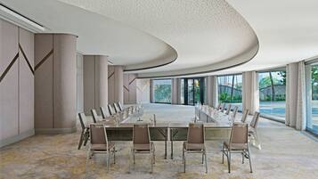 Sala de conferência com uma mesa comprida, cadeiras e design moderno no teto.