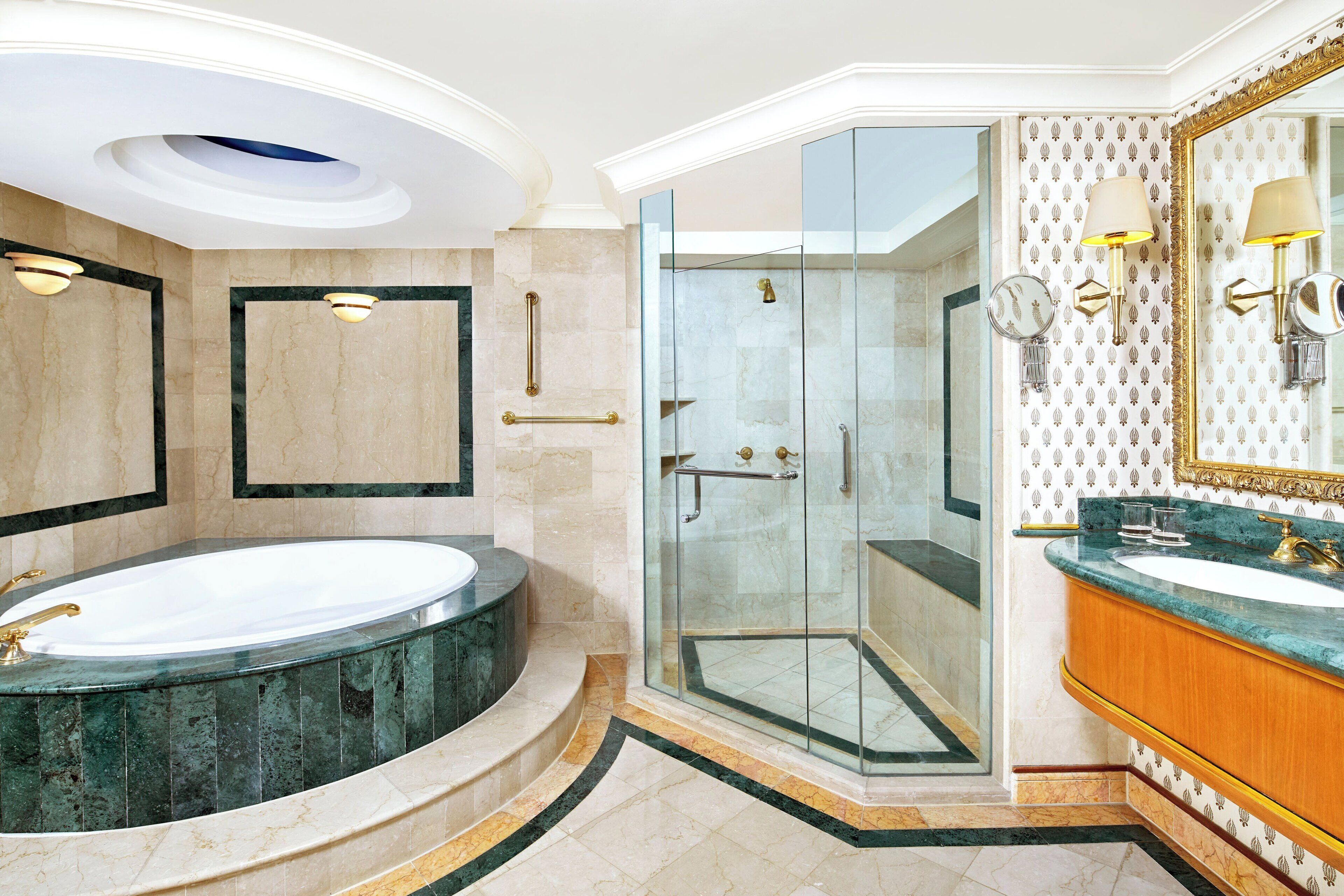 A modern bathroom with a large bathtub, a glass-enclosed shower, and a vanity with a mirror and wall sconces.