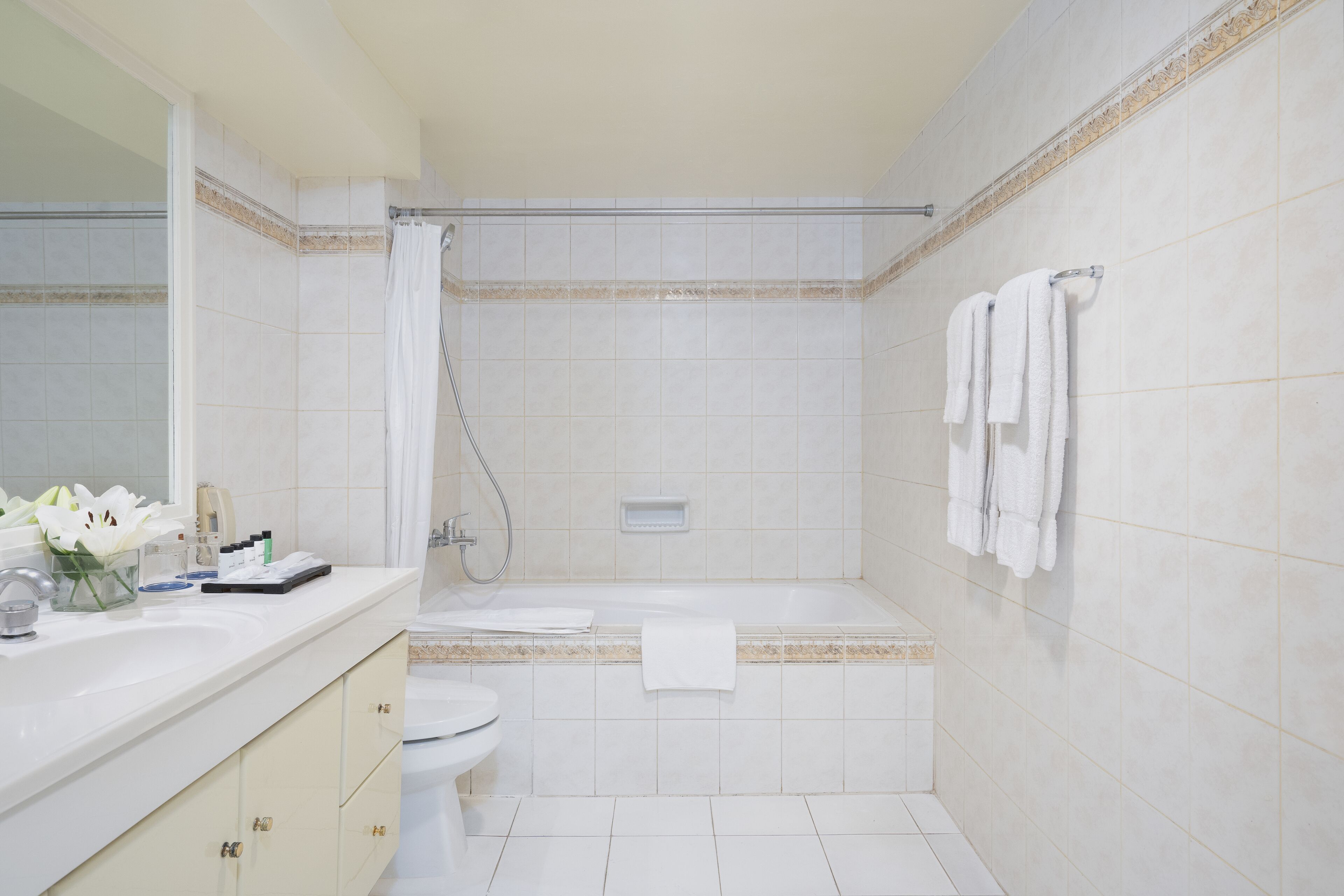 Ein Badezimmer mit Badewanne, Toilette und Waschbecken. Handtücher hängen an der Wand, und ein Duschvorhang ist angebracht.