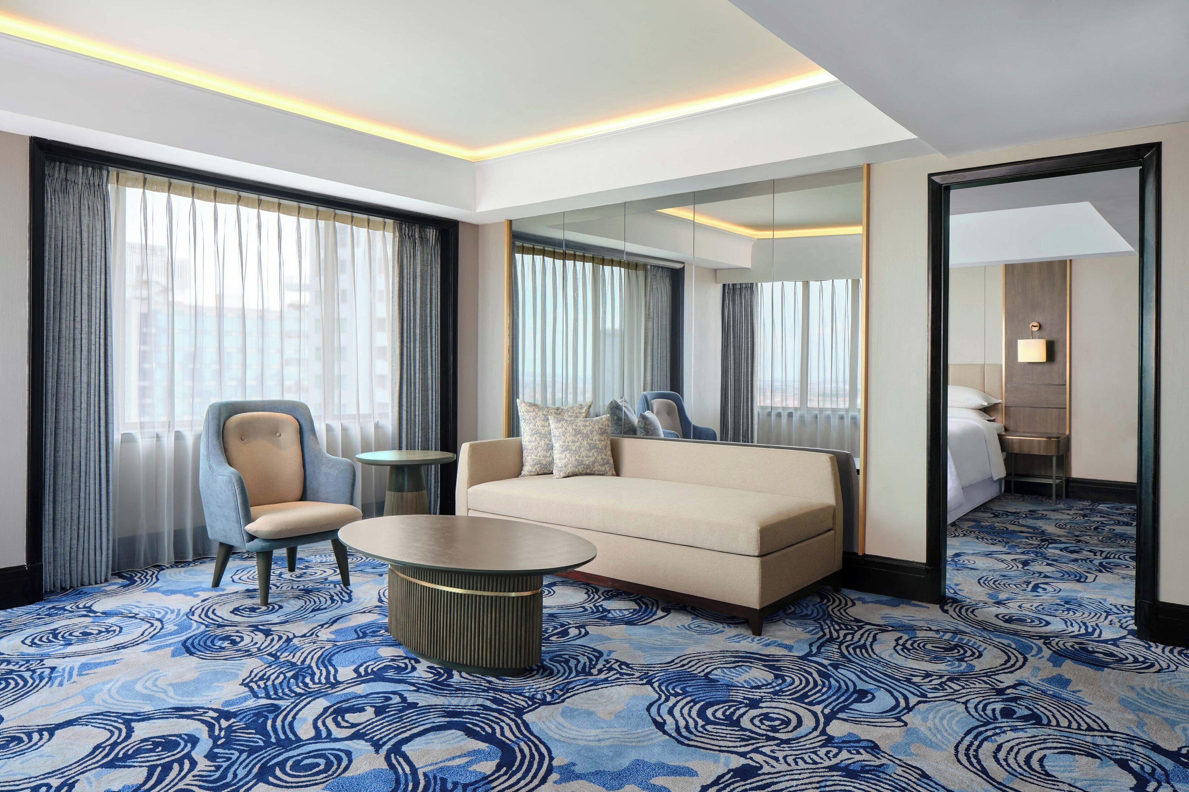 Ein Hotelzimmer mit einer Couch, einem Sessel und einem kleinen runden Tisch.