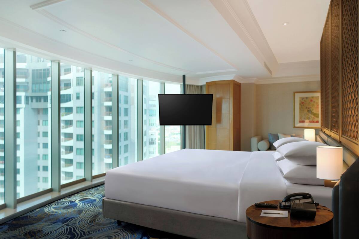 Une chambre d’hôtel avec un grand lit, une table de chevet avec une lampe, un téléphone et un téléviseur fixé au mur.