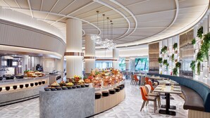 Un hall d’hôtel moderne avec un comptoir d’accueil incurvé, des espaces de détente et un buffet.