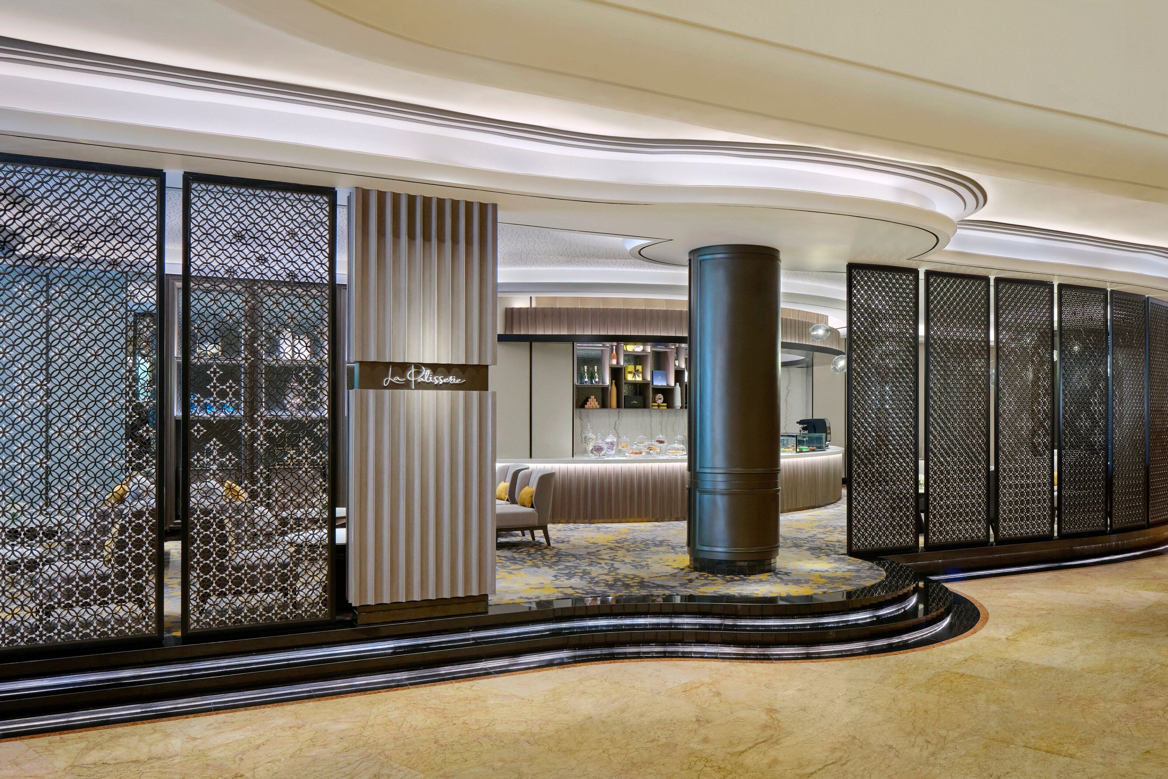 En modern hotellobby med en central sittgrupp, en receptionsdisk och en dekorativ pelare.