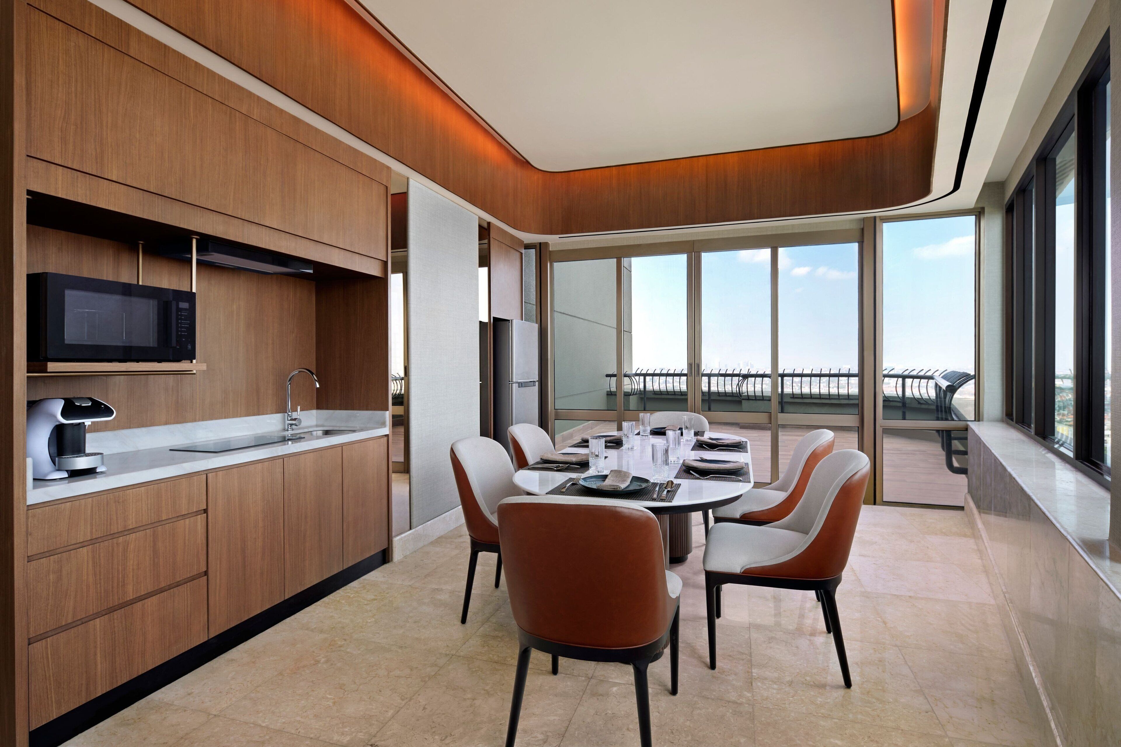 A modern kitchen with a built-in microwave, a coffee machine, and a large window overlooking a balcony.
