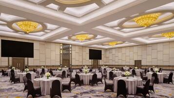 A large conference room with multiple round tables, black chairs, and chandeliers.