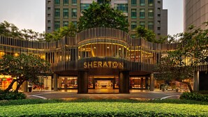 Entrée de l’hôtel Sheraton, caractérisée par un design moderne, de grandes colonnes et une façade bien éclairée.