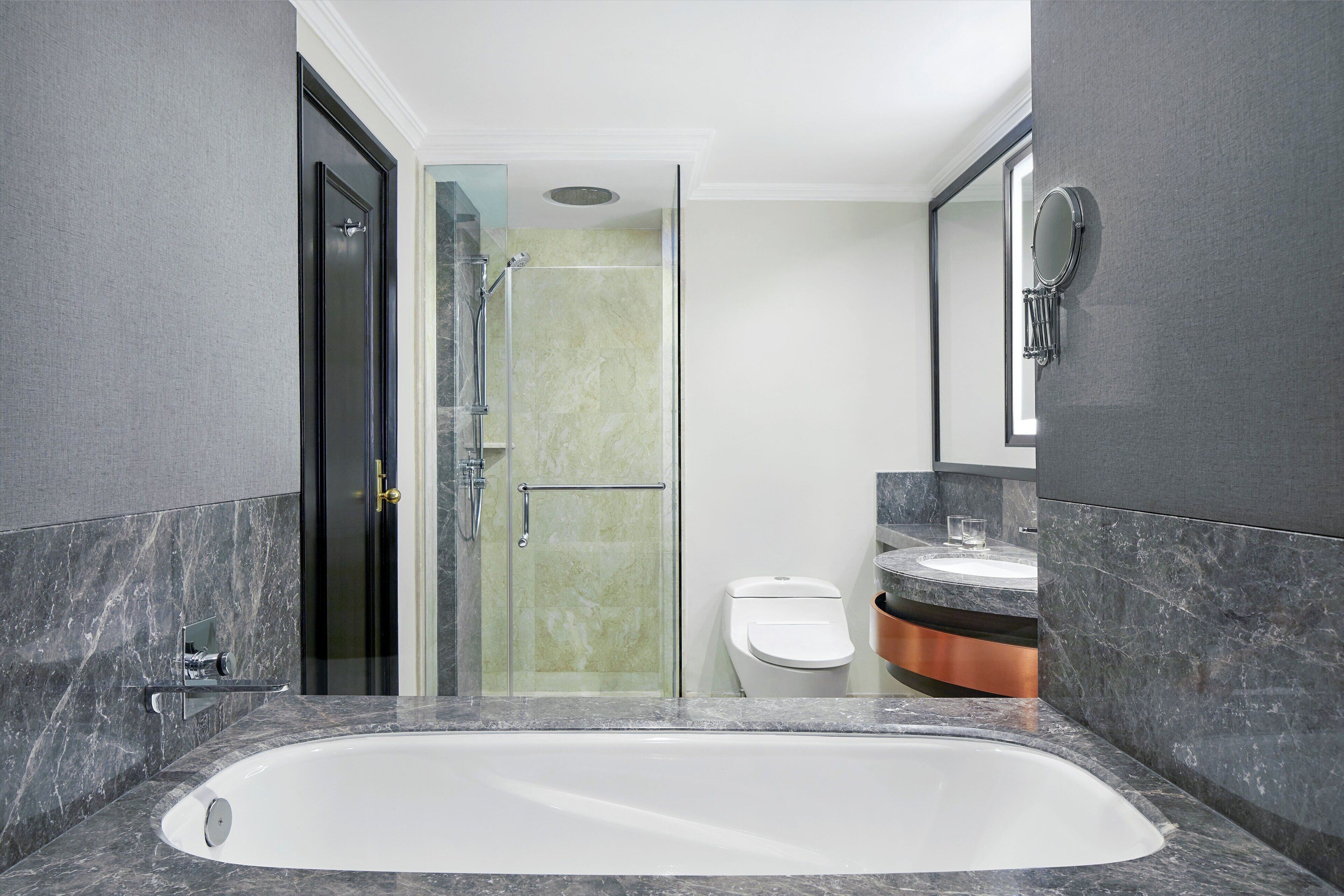 A modern bathroom with a large bathtub, a glass shower enclosure, and a toilet.
