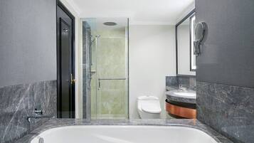 A modern bathroom with a large bathtub, a glass shower enclosure, and a toilet.