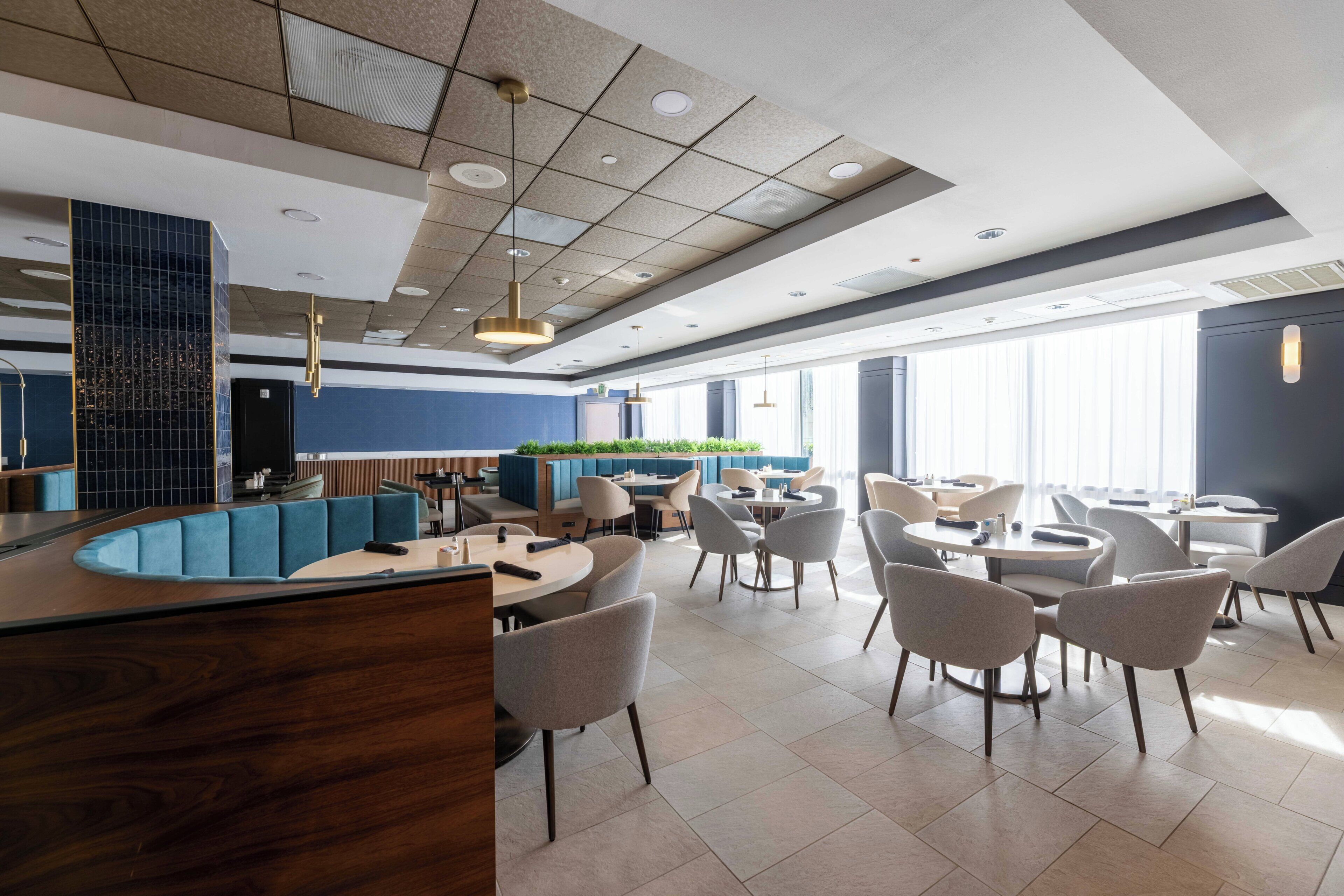 A modern restaurant with a curved counter, round tables, and chairs.