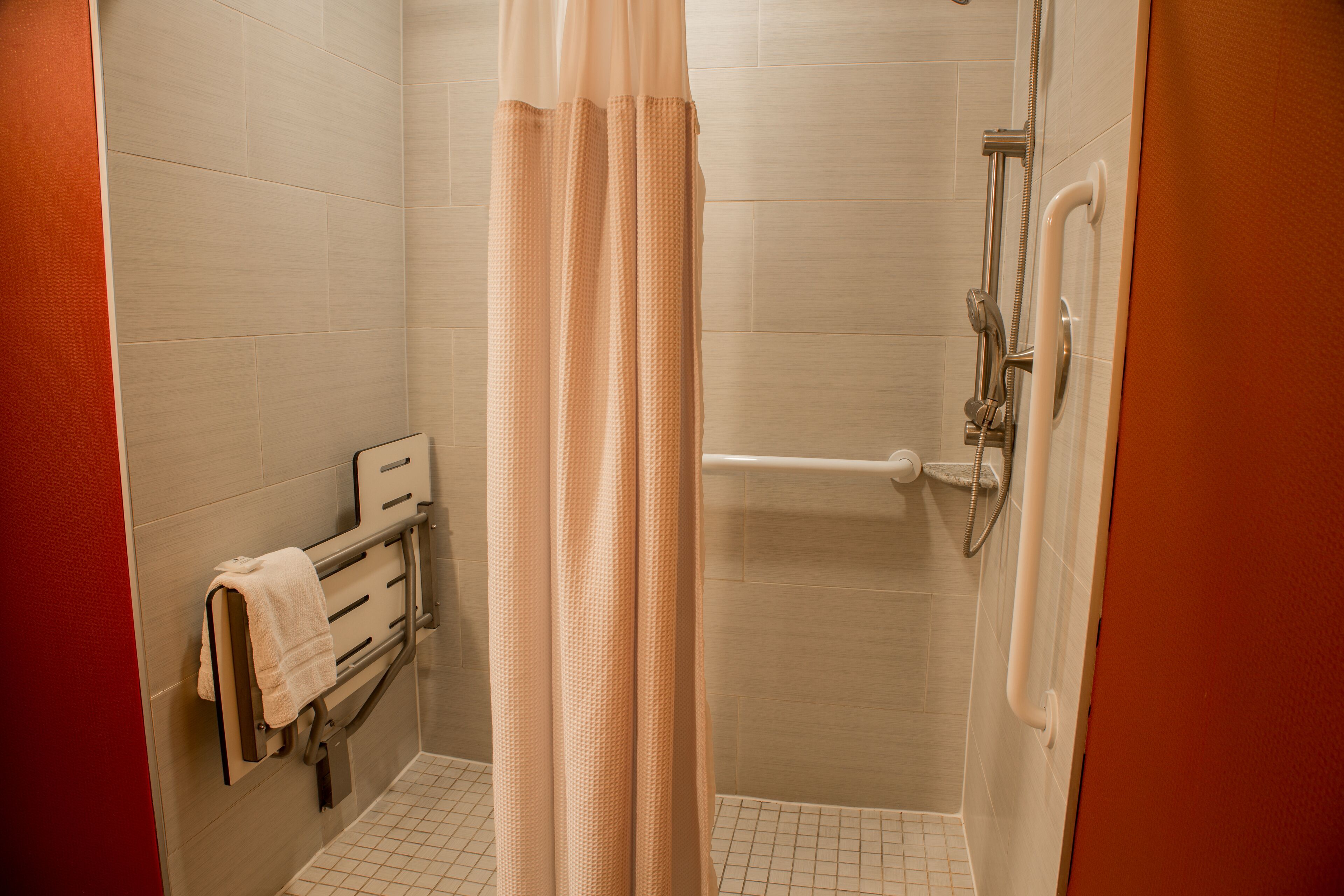 A shower area with a glass door, a towel rack with a towel, and a shower control panel.