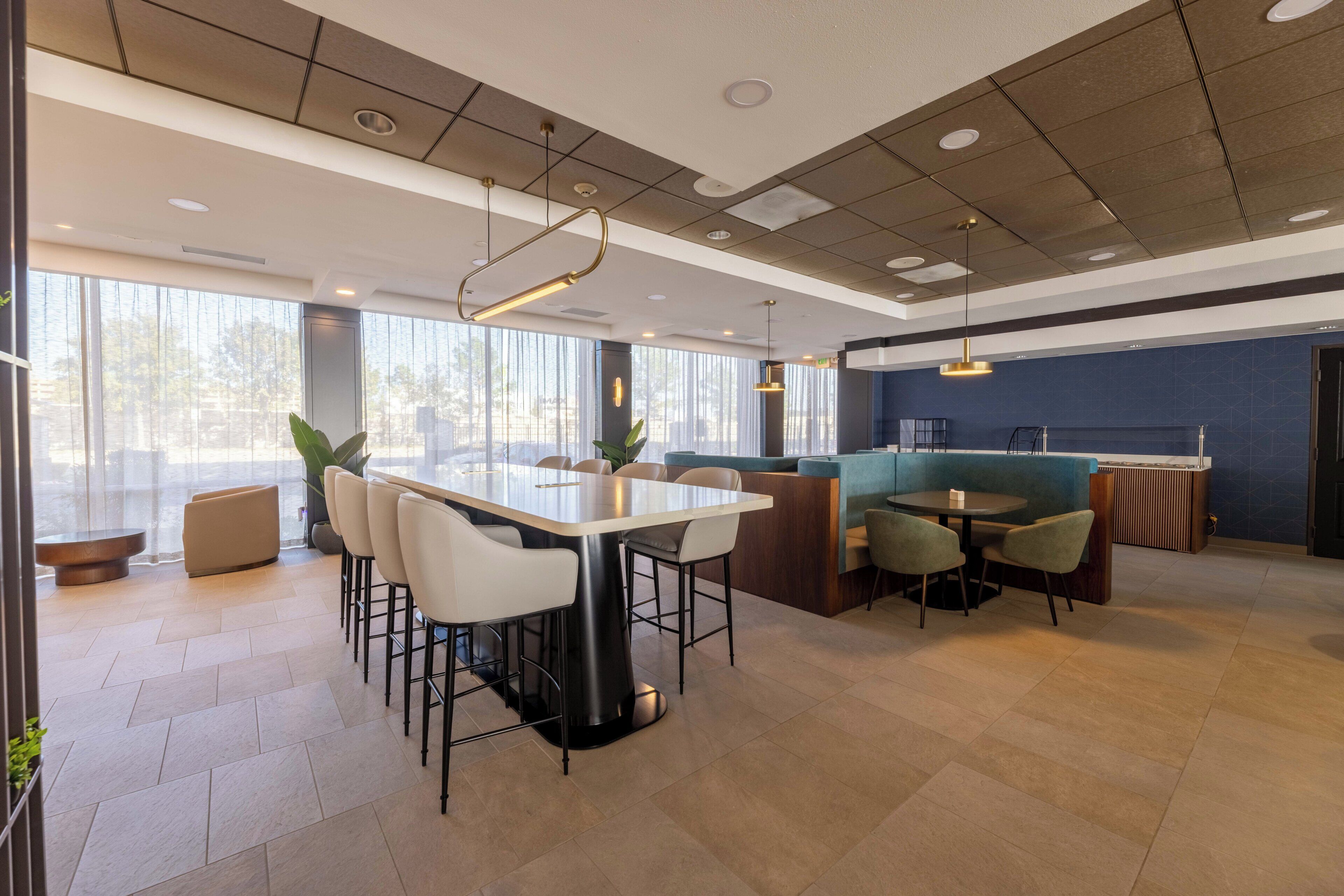A modern restaurant with a large dining table, bar seating, and a counter.