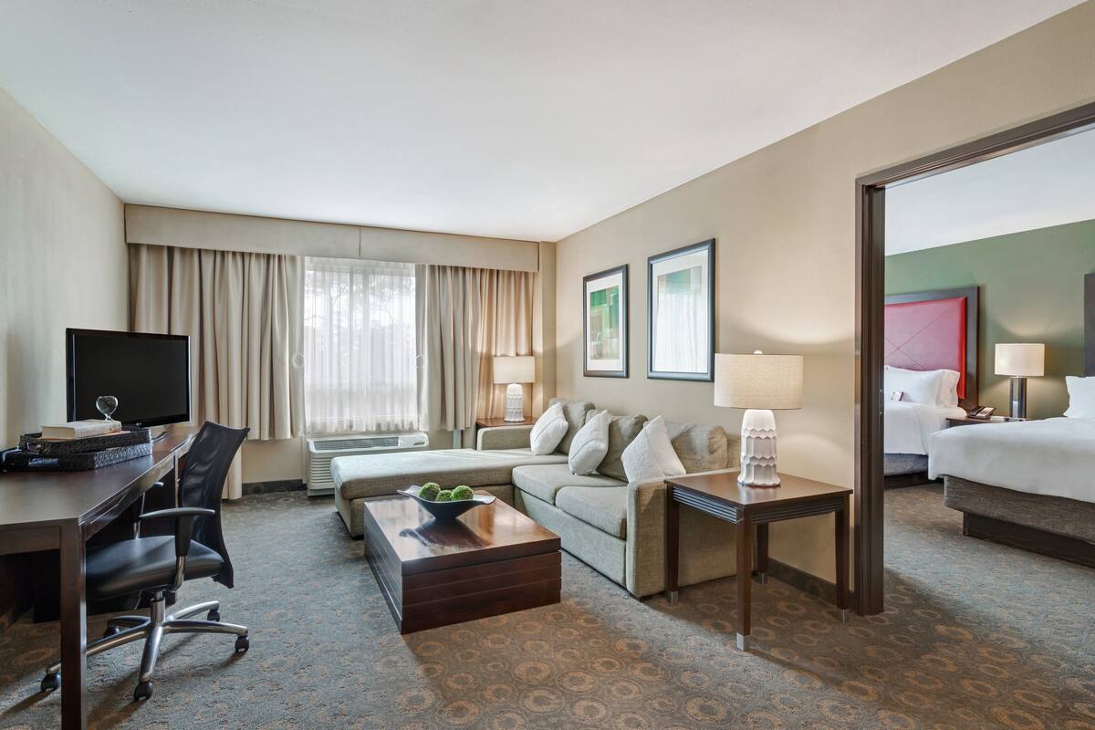 A hotel room with a desk, a sofa, a bed, and a coffee table.