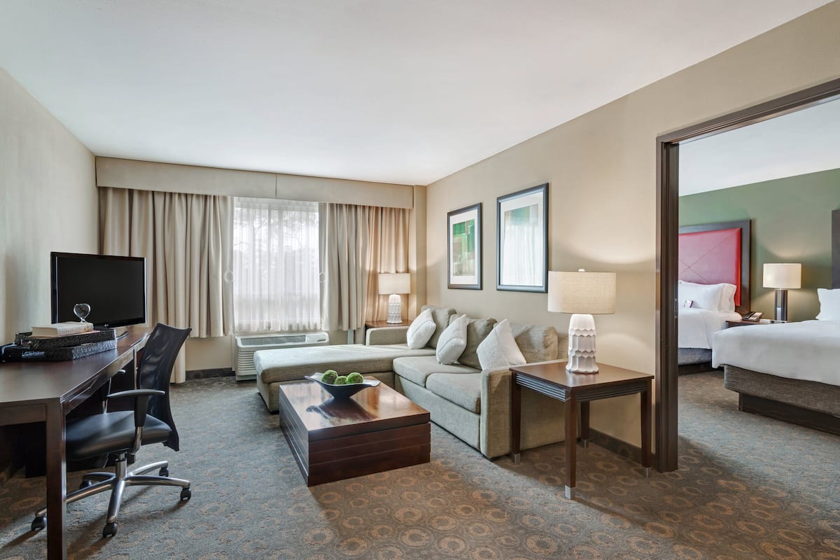 A hotel room with a desk, a sofa, a bed, and a coffee table.