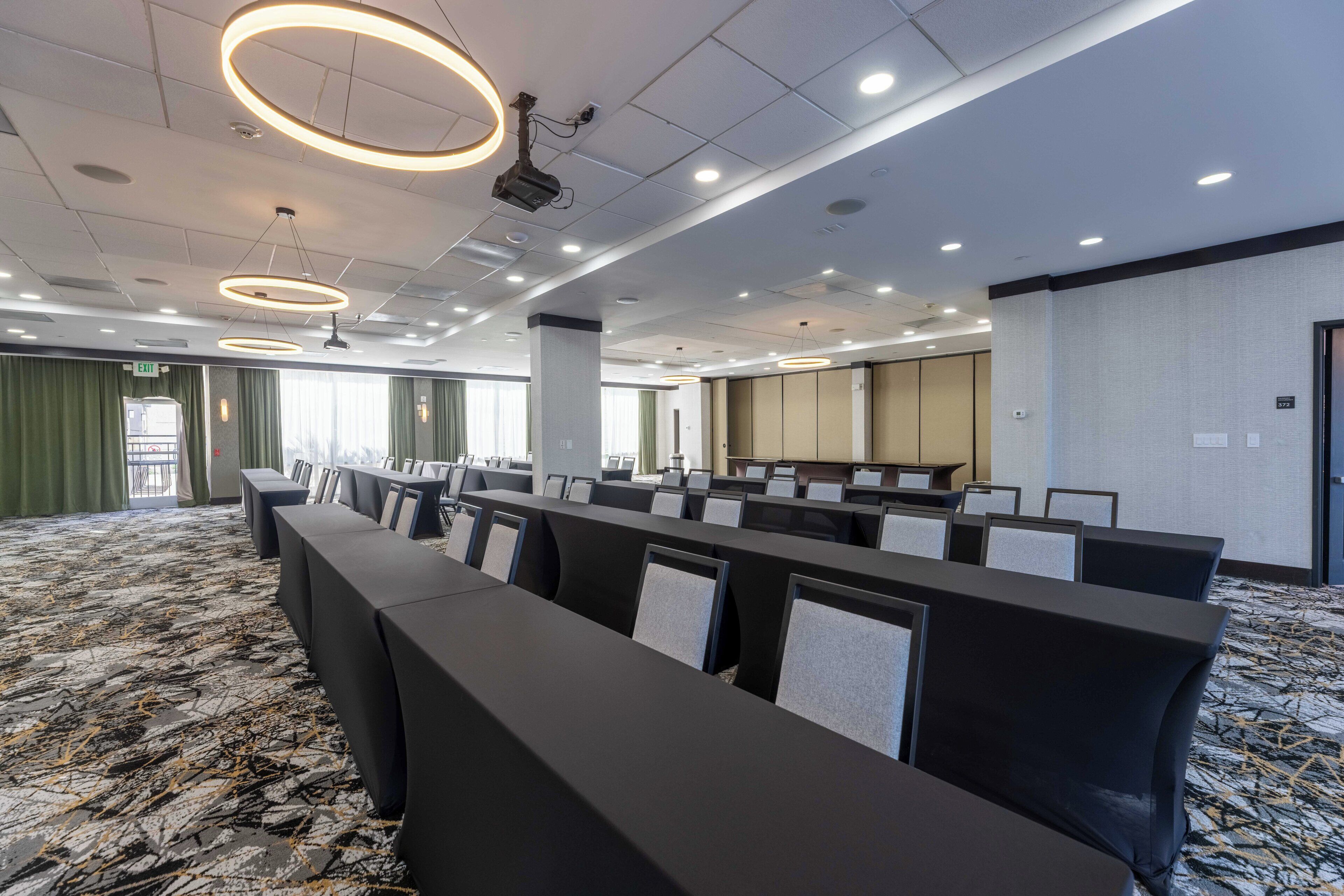 A conference room with rows of tables and chairs, a patterned carpet, and modern lighting fixtures.