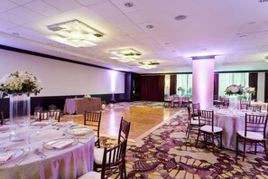 A banquet hall with round tables set for dining, large floral centerpieces, and a patterned carpet. - Crowne Plaza Houston Galleria Area by IHG (Houston)
