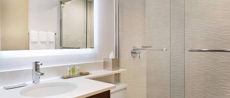 Un baño moderno con un espejo grande, un lavabo y una cabina de ducha.