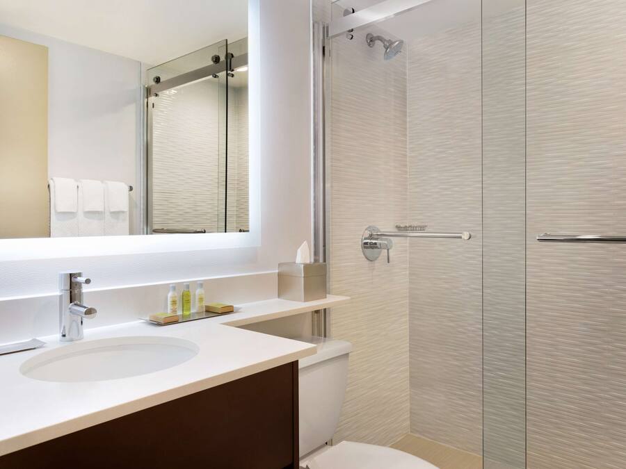 A modern bathroom with a large mirror, a sink, and a shower enclosure.